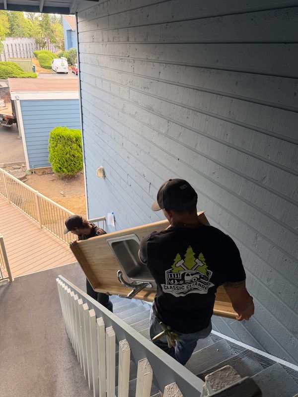 Crew carrying an old countertop and sink down an outdoor staircase