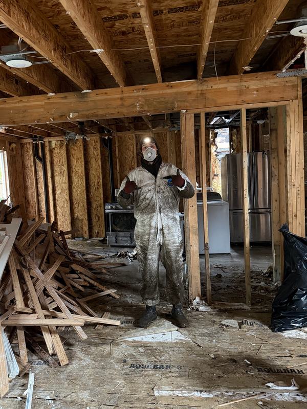 Classic Cleanouts crew member in protective gear inside a home taken down to the studs during a restoration tear-out